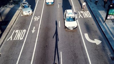 High angle view of a woman crossing a road. City streets, asphalt, bike lanes, car  traffic, pedestrians