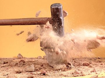 Sledgehammer breaking rocks. (demolishing, crushing, blurred motion)