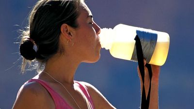 water. A young exercising woman stops and drinks from a water bottle. drinking water